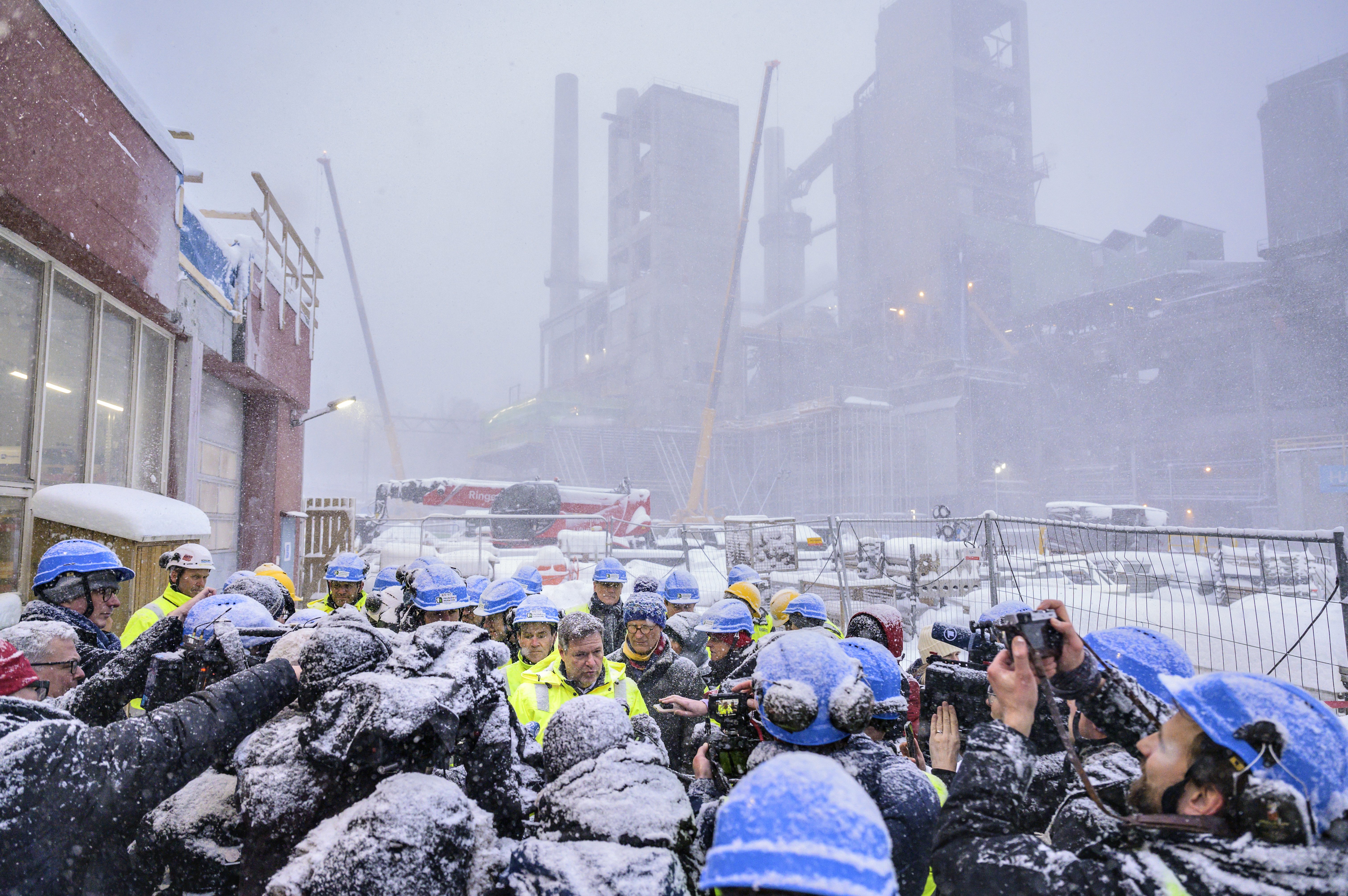 Man being interviewed and photographed on a snowy industrial site